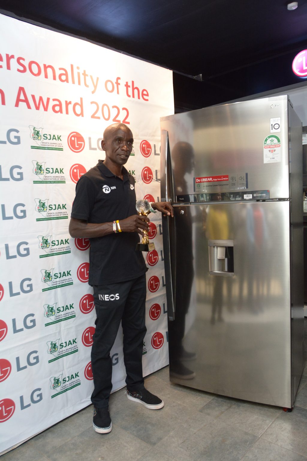 Eliud Kipchoge with his trophy and fridge.